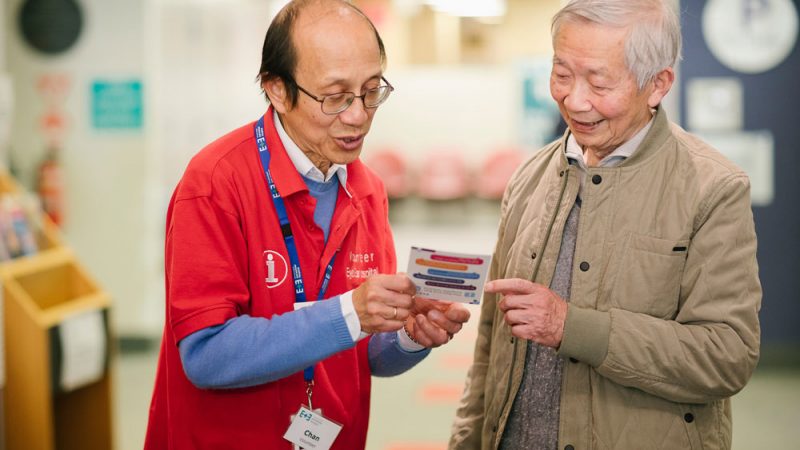 A hospital volunteer giving information to an older man