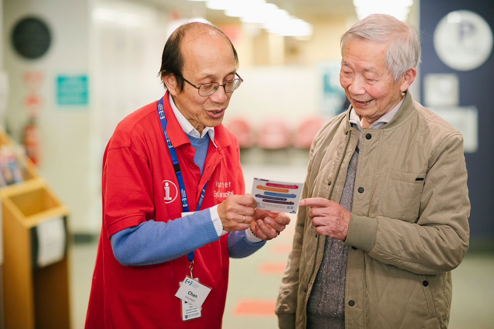 A hospital volunteer giving information to an older man