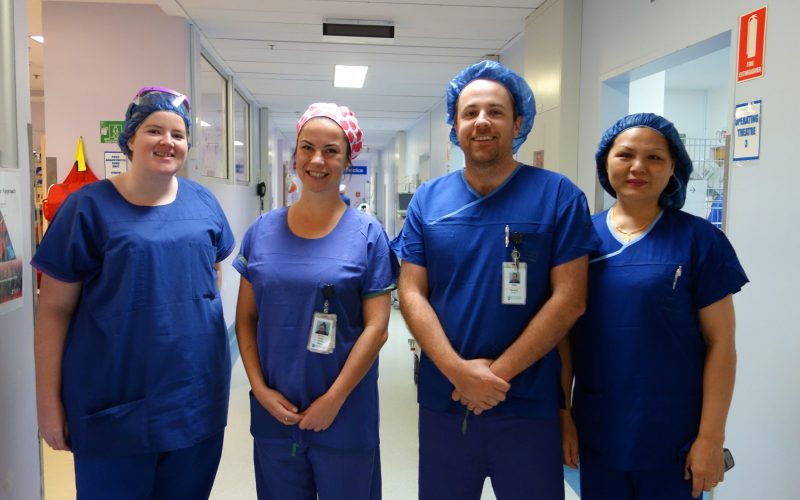 4 smiling nurses in blue scrubs