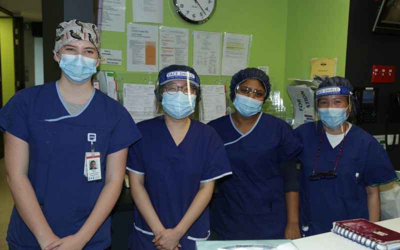 ER nurses in full PPE gear. Smiling together