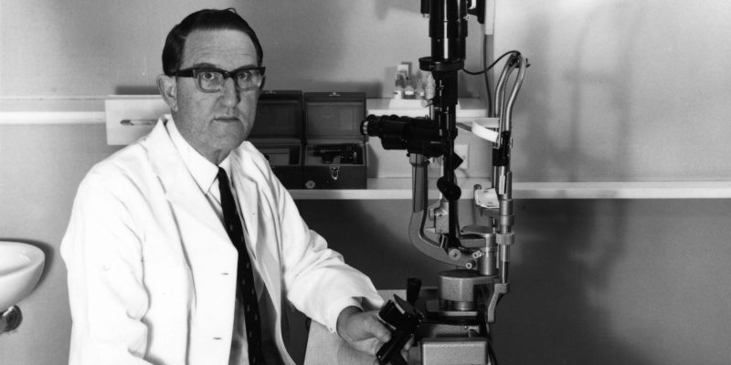 Black and white photo of doctor in front of an medical device