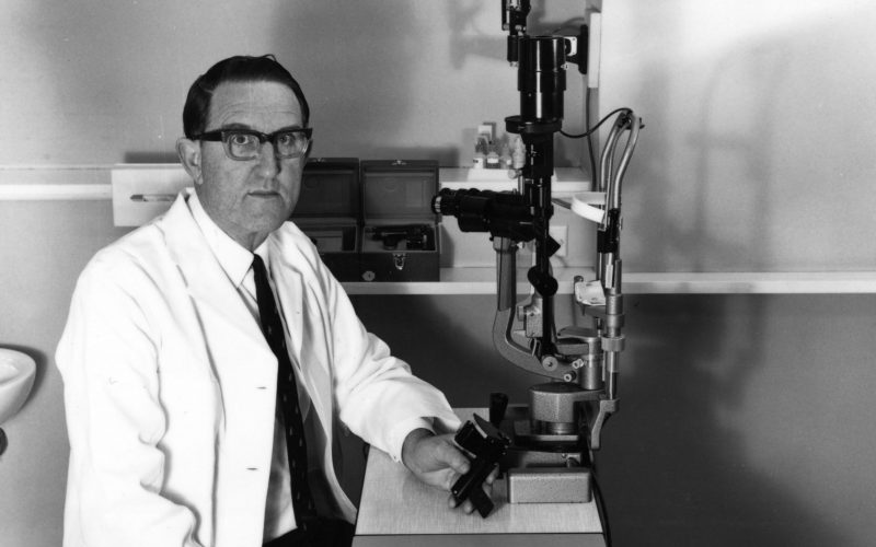 Black and white photo of doctor in front of an medical device