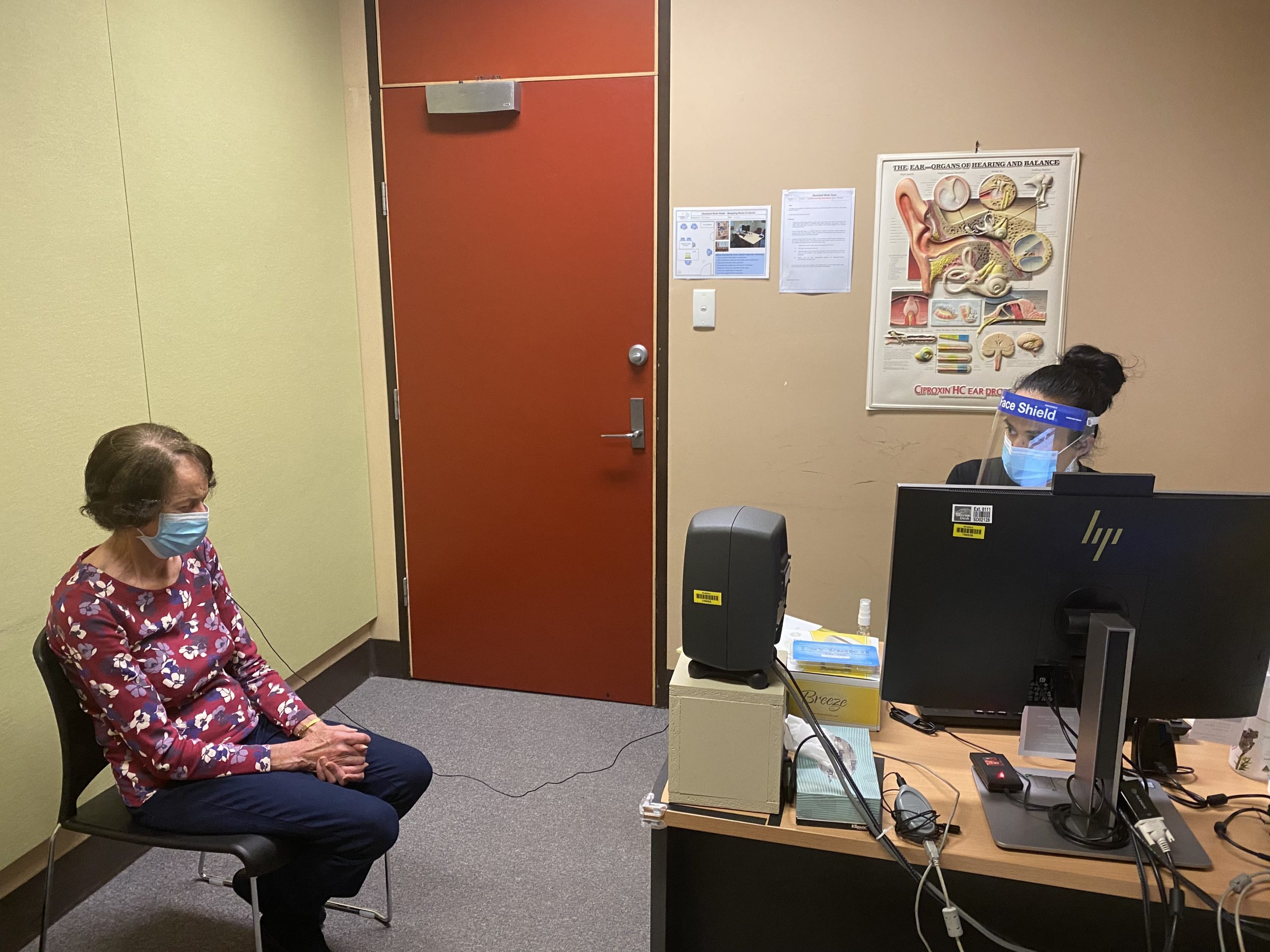 Lanna having her cochlear implant tested by a doctor at the eye and ear. She is sitting in a chair and the doctor is at a computer