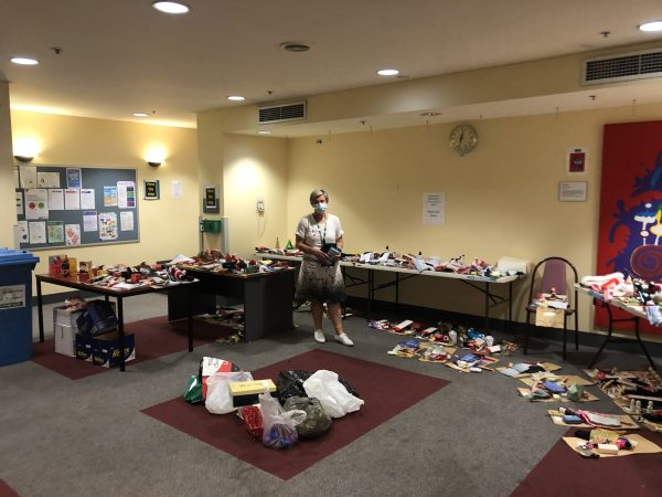 Debra Hailes smiling, standing with dozens of christmas hampers