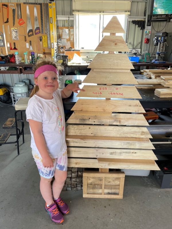 Cochlear Implant patient Katie standing next to the wooden Christmas tree she made with her grandfather