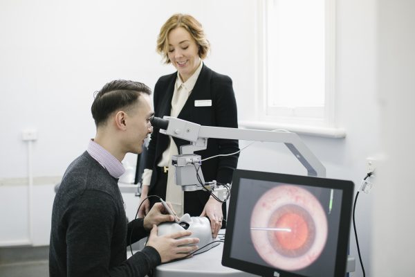 A photo of DR Beltz teaching a student looking through a microscope