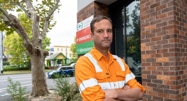 Man wearing a an orange hi-vis top with his arms crossed