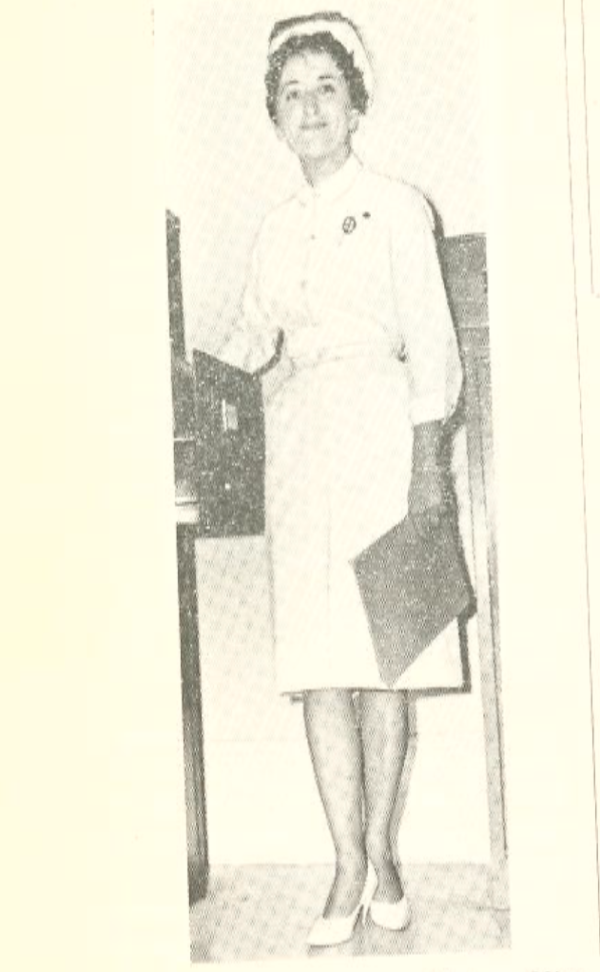 A black and white photo of a woman in a white nursing outfit , wearing white high heels and holding a clipboard.