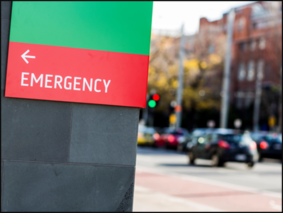 Image of emergency sign with traffic lights in the background