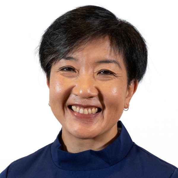 Headshot of a middle-aged female with black short hair smiling, wearing a dark blue jacket.