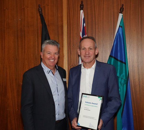 CEO Brendon Gardner smiling with Dr Chris Brown as he holds his award