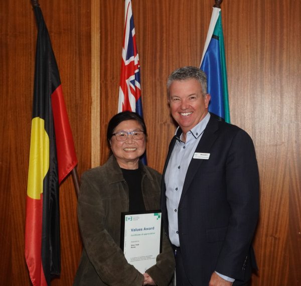 CEO smiling next to Siew Yeak who is holding her awards