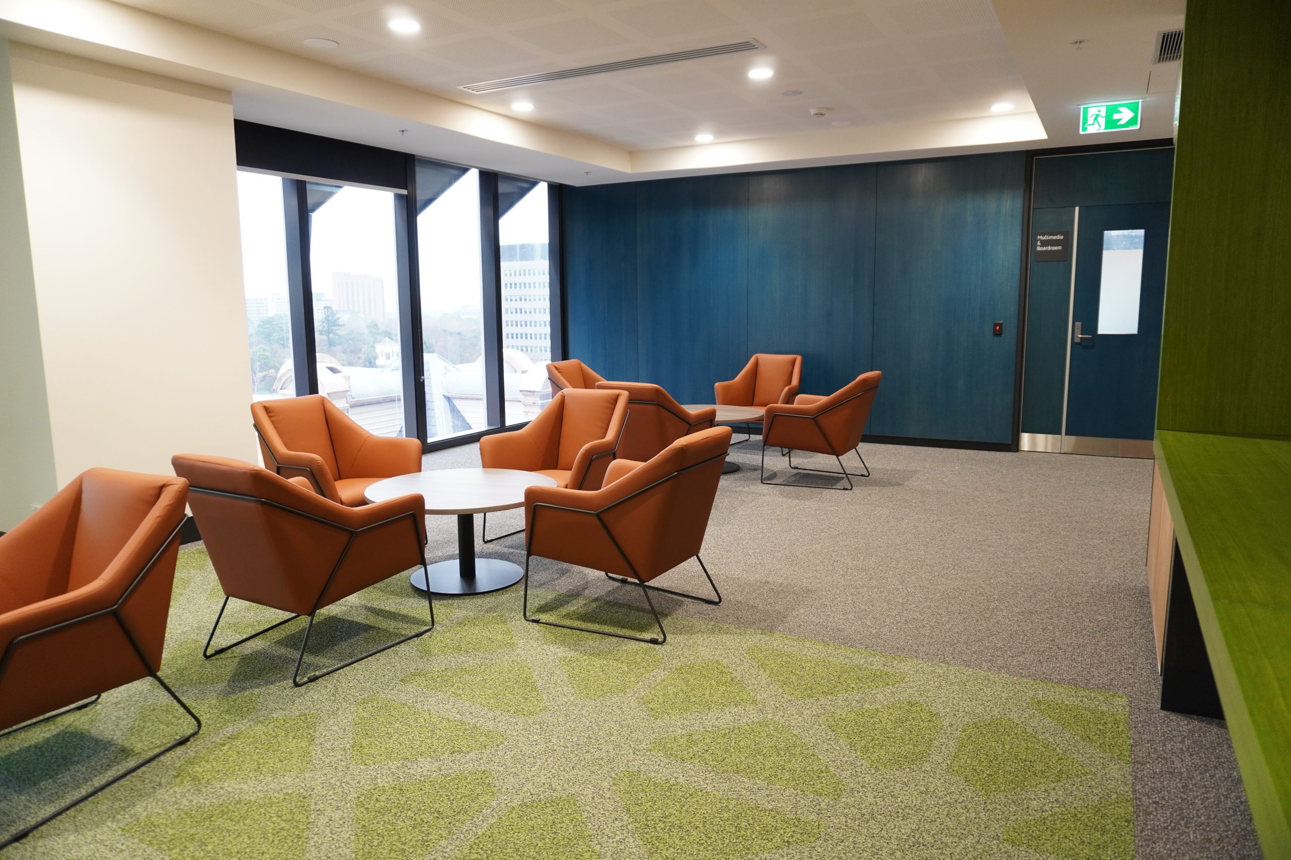 Tables and chairs next to large windows in the Collaboration space