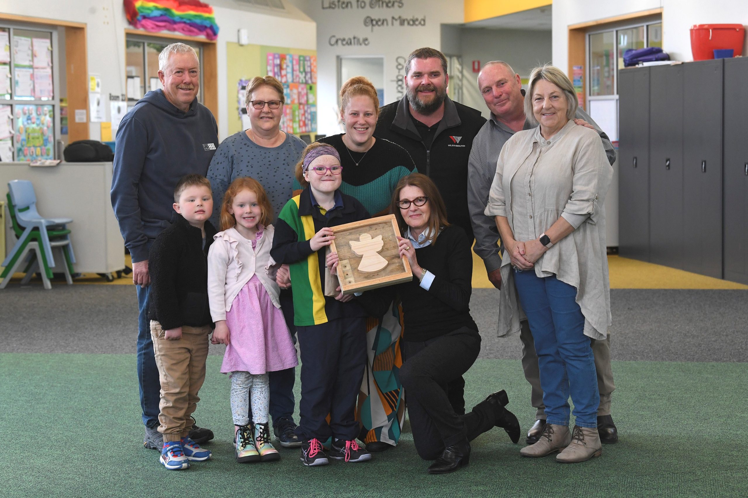 Katie is pictured with her family, grandparents David and Linda Mill,parents Rebecca and Tim Schumann, grandparents Lee and Vikki Schumann, brother Jax and sister Bella, and hospital speech pathologist Denise Courtenay. 