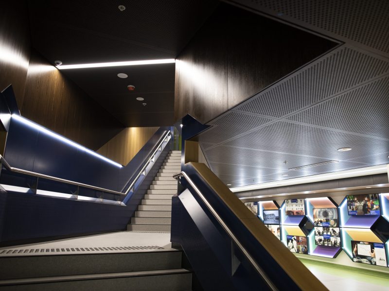 Image of our Ground Floor staircase leading up to Level 1 specialist clincis. In the background you can see the colourful history wall that adorns the walkaway