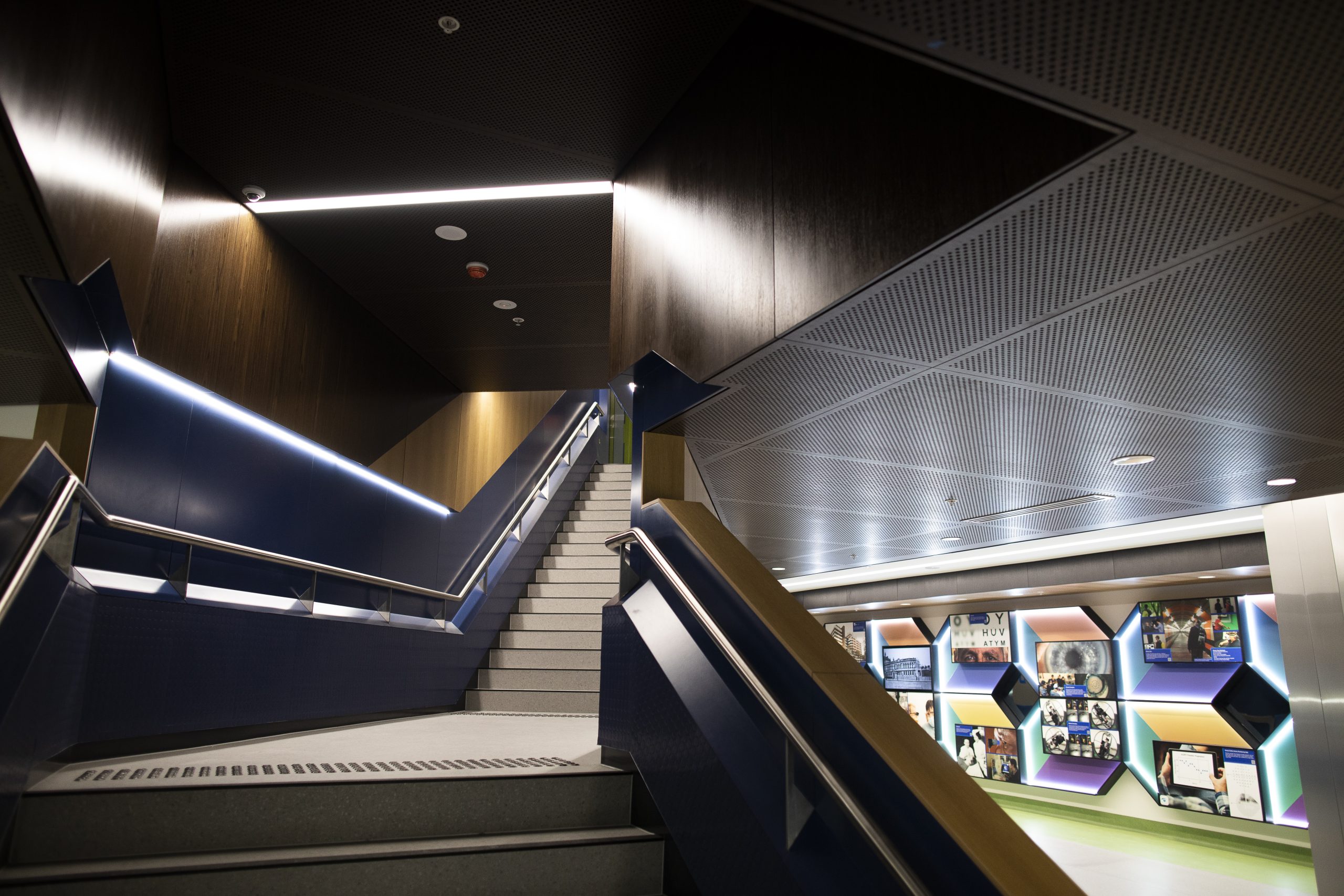 Image of our Ground Floor staircase leading up to Level 1 specialist clincis. In the background you can see the colourful history wall that adorns the walkaway