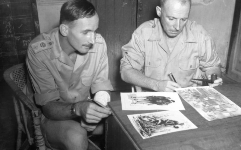 Sir Weary Dunlop and Lieutenant Colonel A. E. Coates, sitting at a desk looking and images prisoners of war drew in Thailand