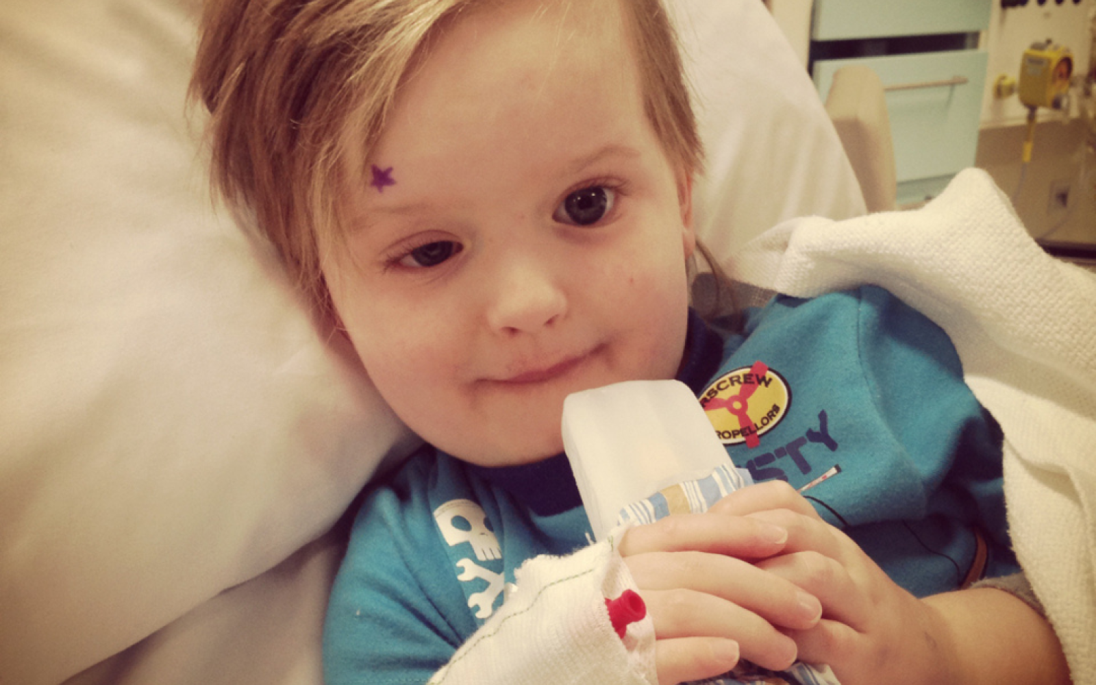 A young boy sits in a hospital bed