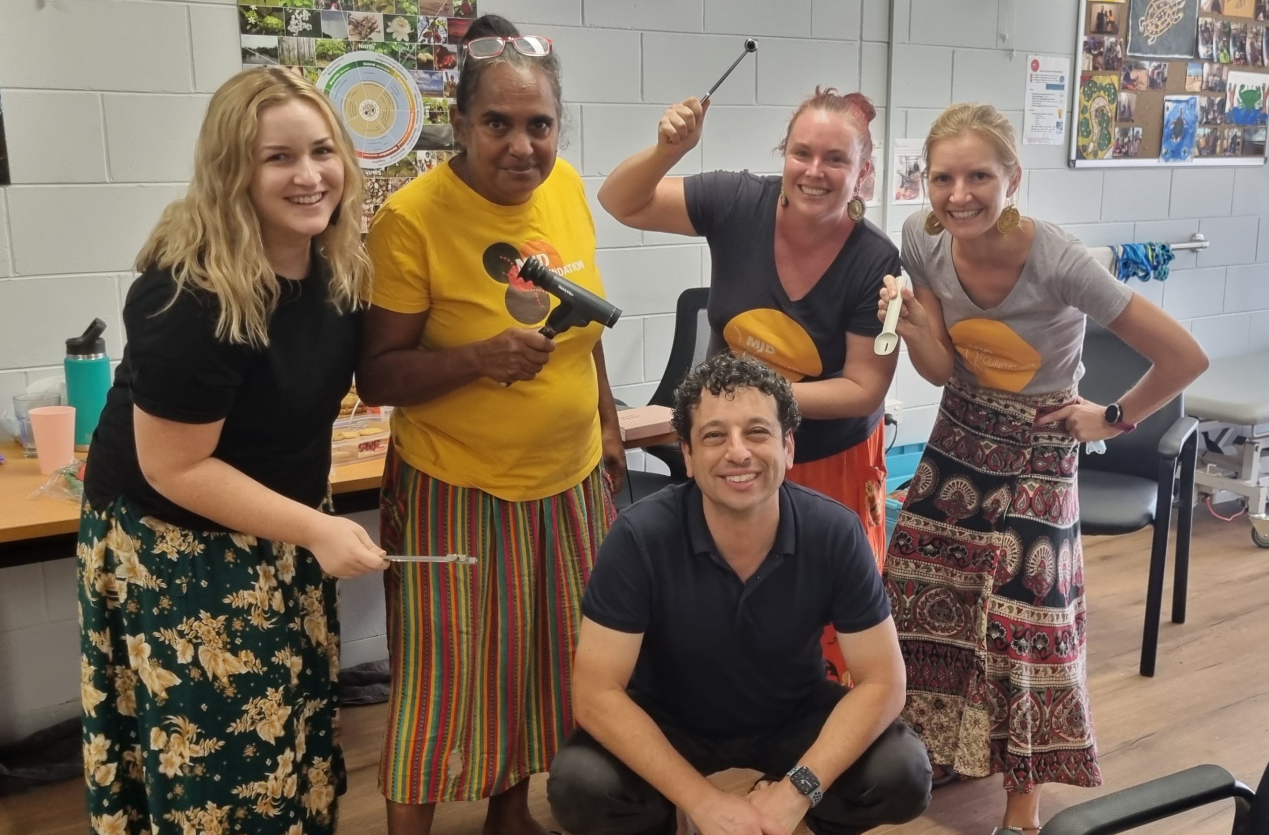 Five people smile at the camera, holding simple diagnostic tools