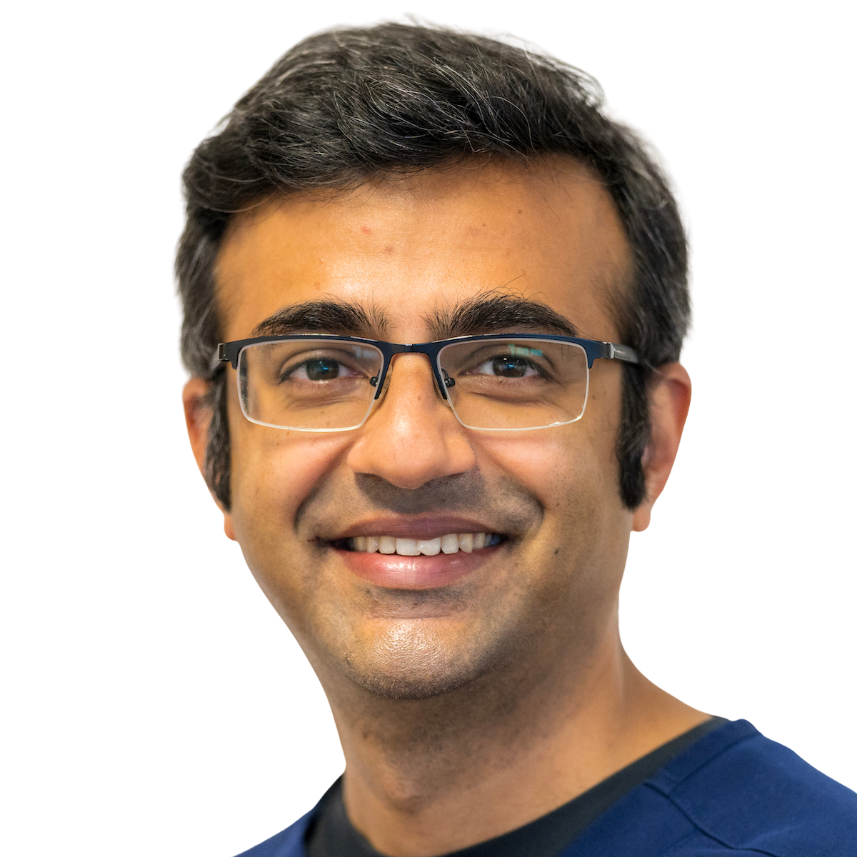 A smiling headshot of Dr Sheth wearing glasses and a blue scrub top