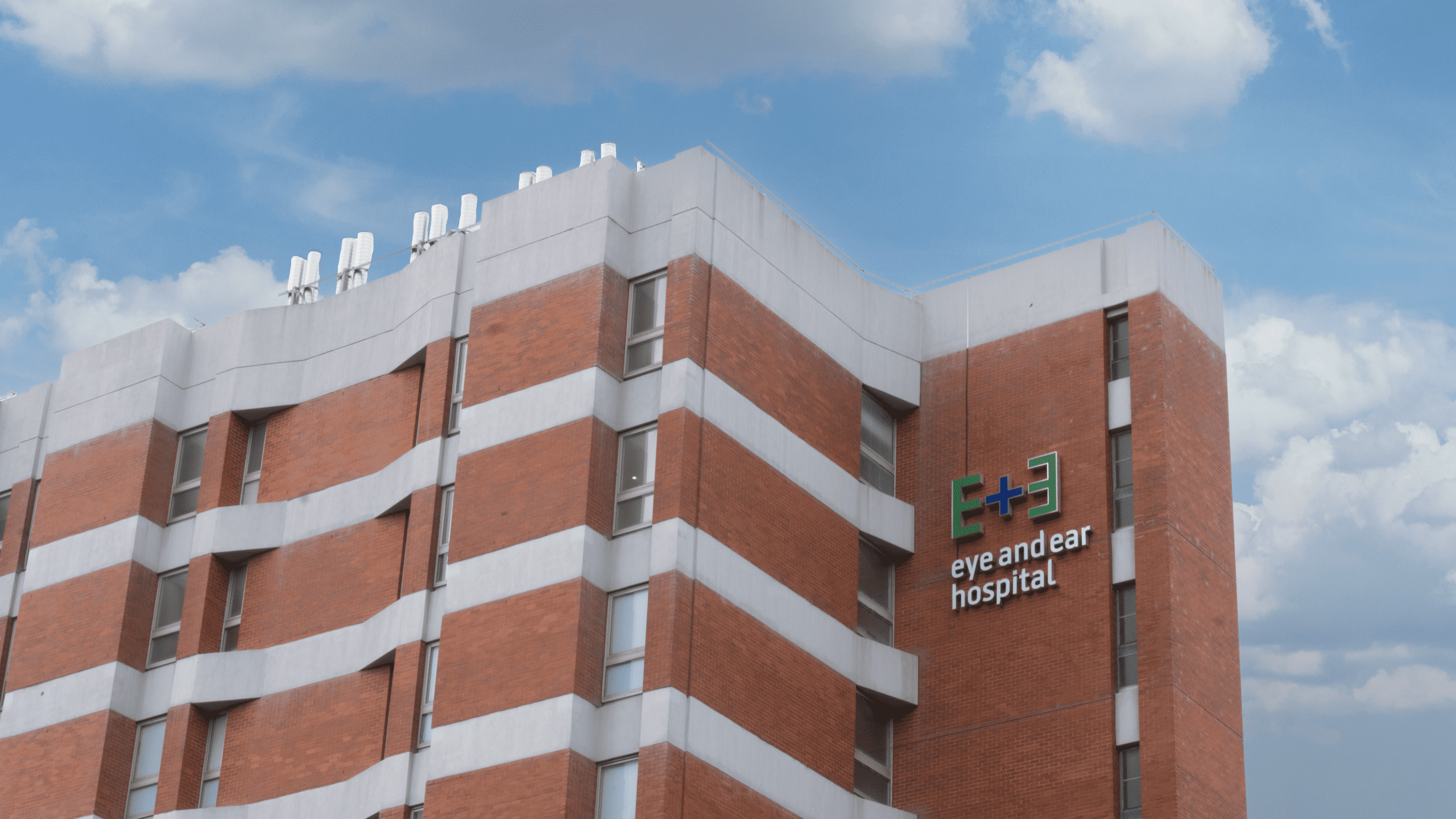 A photo of the Eye and Ear building, showcasing the Eye and Ear logo sky sign against red brick