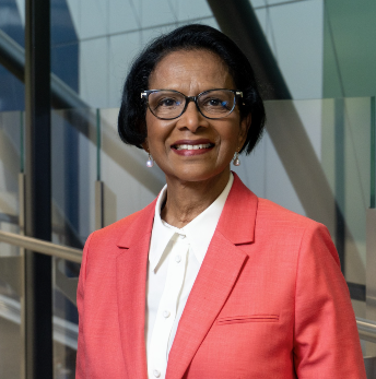 Head shot of Dr Sherene Devanesen smiling at the camera wearing a coral jacket and white top