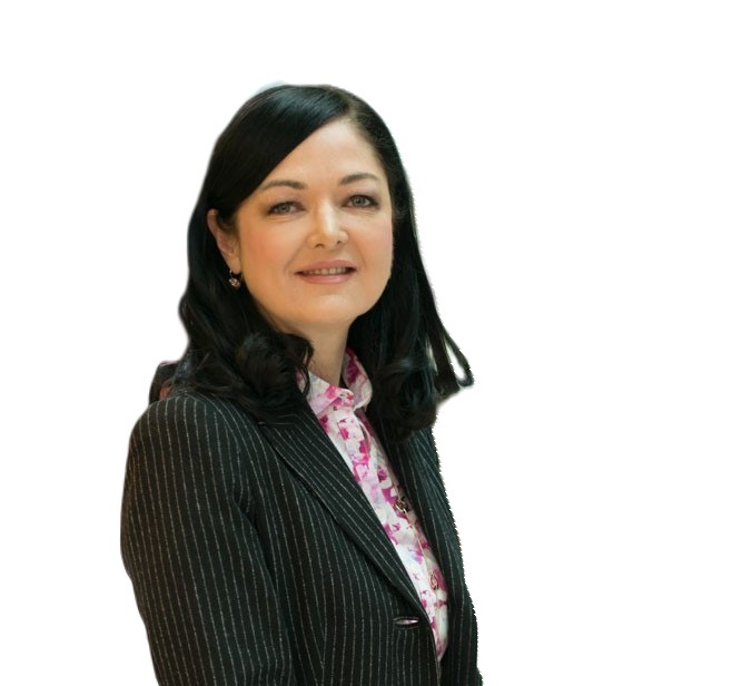 A woman with black hair wears a pin stripe jacket and pink and white blouse. She smiles at the camera.