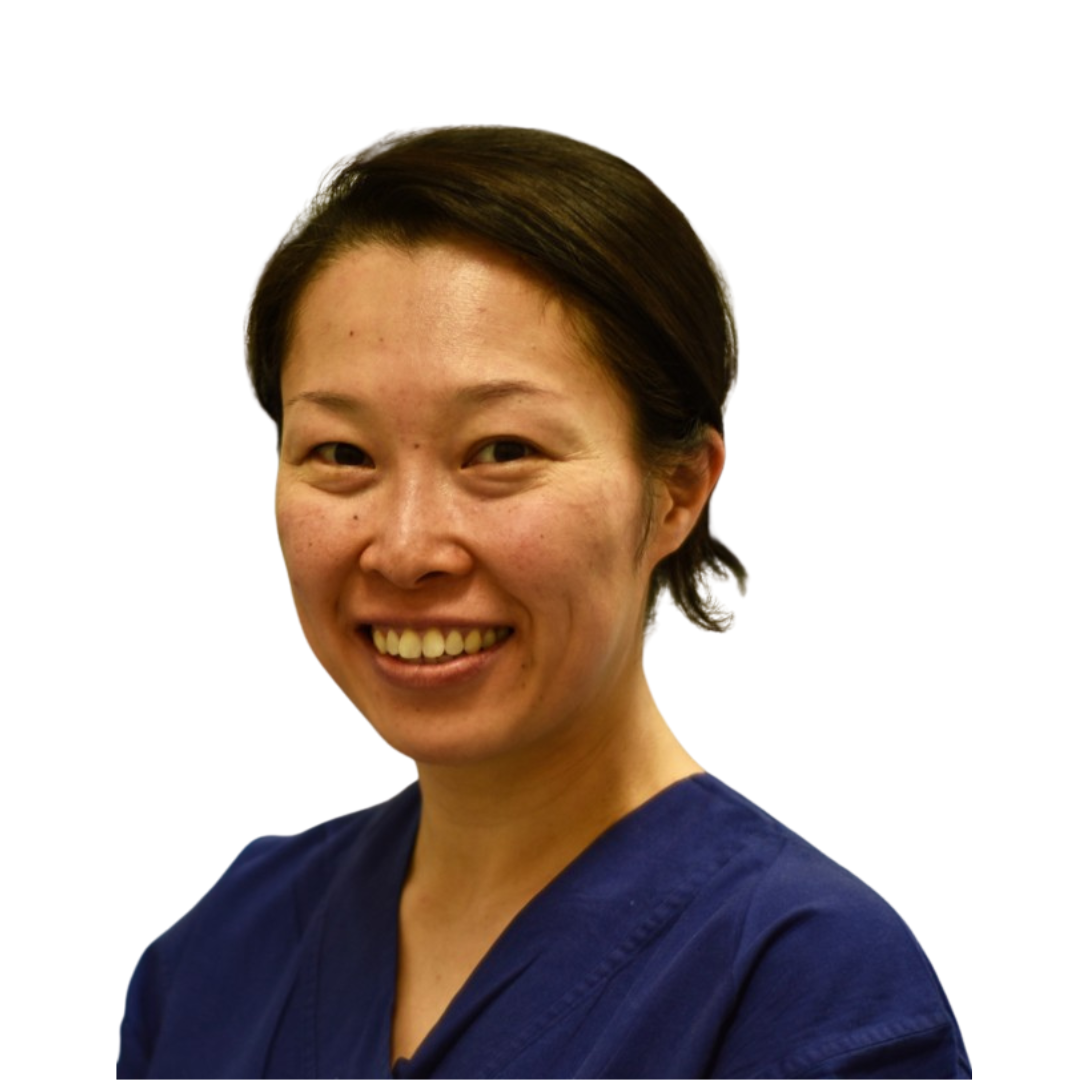 A woman with dark brown hair in a navy scrub top smiles at the camera.