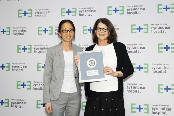 Director of Ophthalmology, Dr Elsie Chan (left) standing with Dr Kristen Wells (right) as she holds her Excellence Award plaque