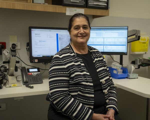 DR Catherine Green AO sitting at a desk with two computer screens behind her.
