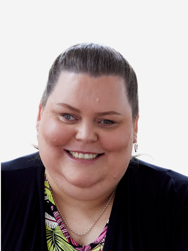 A woman with brown hair pulled back into a pony tail smiles at the camera. She wear's a black blazer over the top of a colourful top.