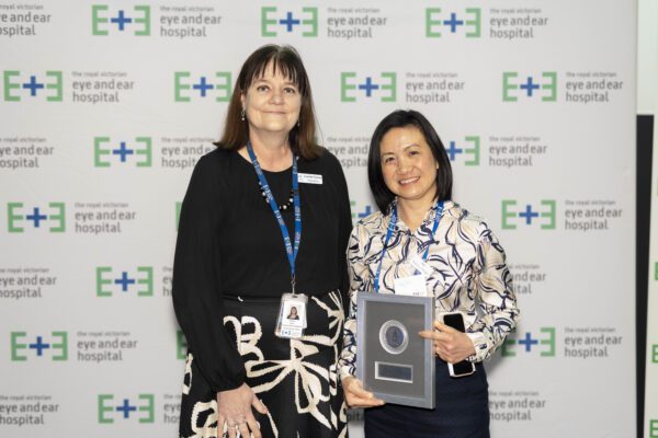 Allied Health winner Ivy Tan holds her award plaque standing next to Executive Director Operations and Chief Nursing Officer Leanne Turner against a white backgroun with eye and ear logos.