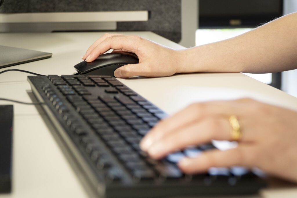 A close up of someone's hands on a keyboard and mouse.