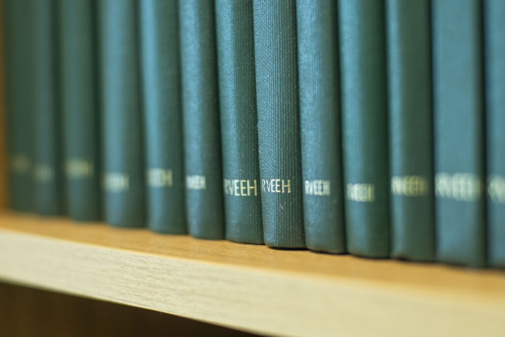 A close up of green spined books on a book shelf.